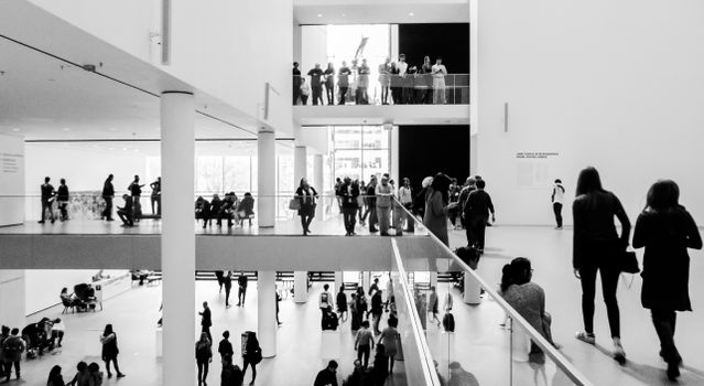 A dynamic black and white image of people in a modern museum setting.