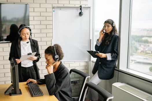 Professional women collaborating in a call center with headsets and computers.